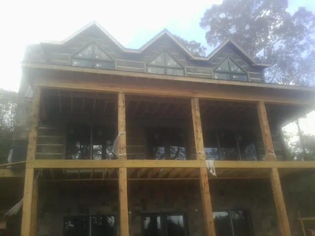 Dormers and porch framing on a large log home under construction — Roof Coating work by our crew in Vanderbilt