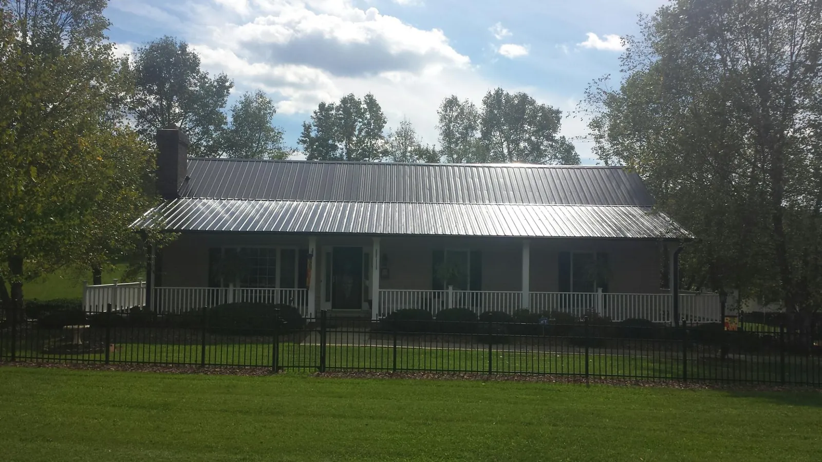 Gray metal roof on a brick ranch with a full width front porch — Gutter Guard Installation work by our crew in Vanderbilt